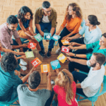 A group of people sitting around a table playing a card game with colorful cards.